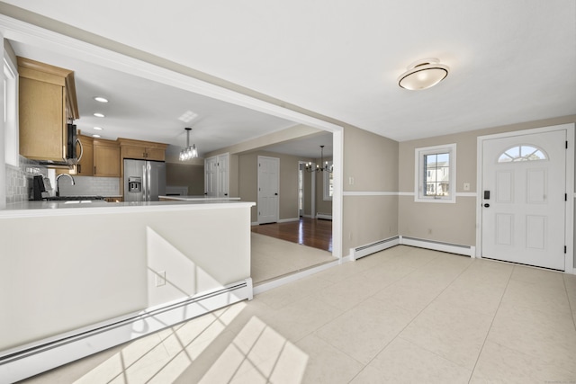 kitchen featuring a baseboard radiator, a peninsula, stainless steel appliances, a notable chandelier, and baseboard heating