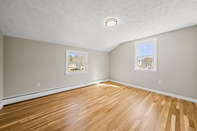 interior space with a wealth of natural light, a baseboard radiator, a textured ceiling, and hardwood / wood-style flooring