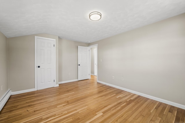 unfurnished room featuring a textured ceiling, baseboards, light wood finished floors, and a baseboard radiator