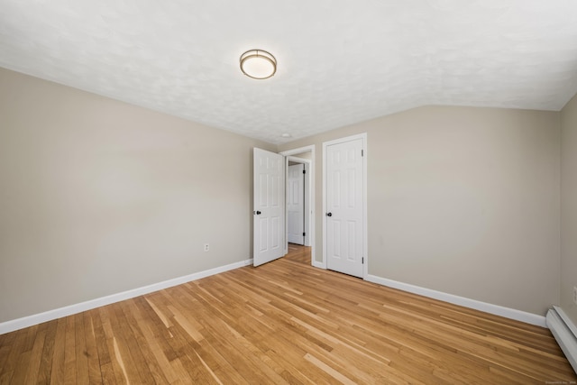 unfurnished bedroom featuring light wood-type flooring, lofted ceiling, a textured ceiling, baseboards, and baseboard heating