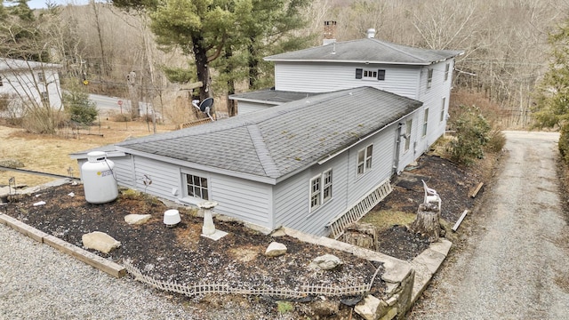 rear view of house with a chimney and roof with shingles