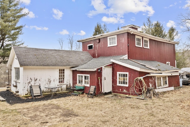 rear view of property with roof with shingles