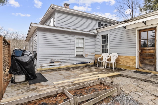 rear view of property with a deck, a vegetable garden, fence, and a chimney