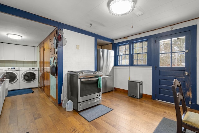 washroom with wainscoting, independent washer and dryer, wood finished floors, and laundry area