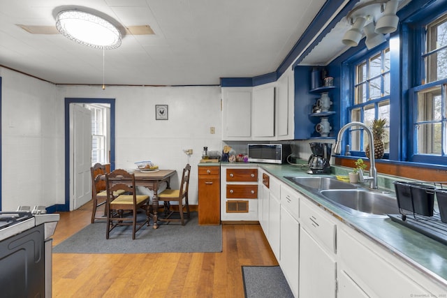 kitchen with white cabinetry, tile walls, light wood-style floors, and a sink