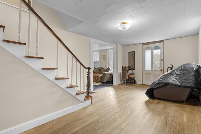 entrance foyer with stairway, baseboards, and light wood-style flooring