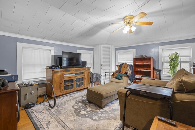 living area with wood finished floors, a healthy amount of sunlight, and ornamental molding