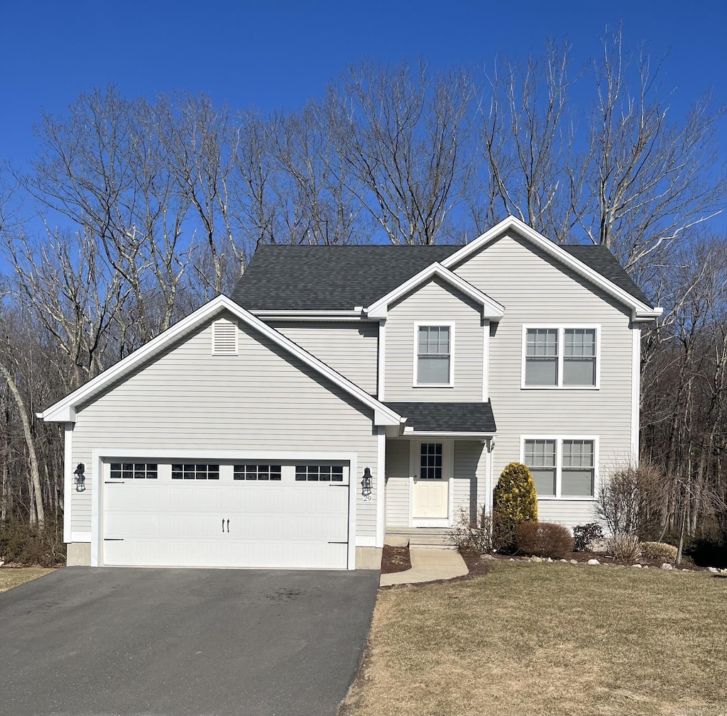 traditional home with aphalt driveway, a shingled roof, a garage, and a front yard