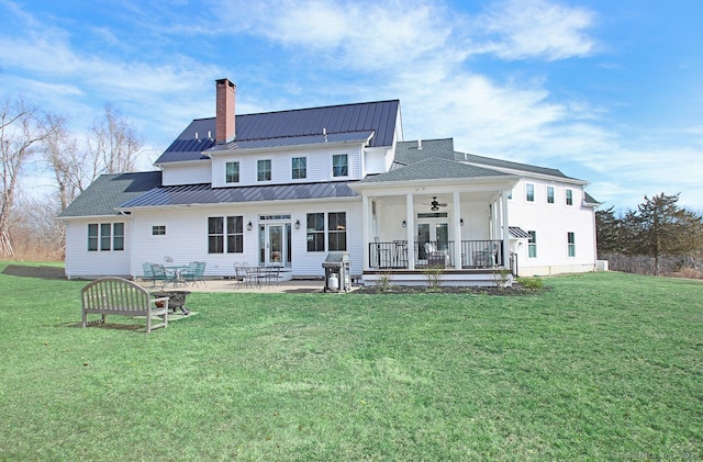 rear view of house featuring a lawn, a ceiling fan, a standing seam roof, french doors, and a chimney