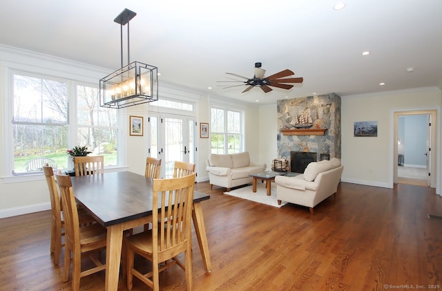 dining space featuring plenty of natural light, a fireplace, crown molding, and wood finished floors