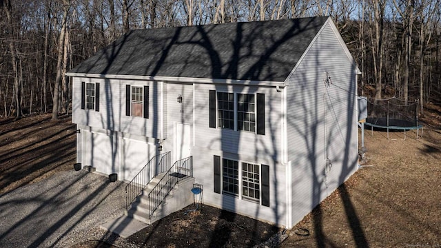 view of outbuilding featuring a garage, a trampoline, and driveway