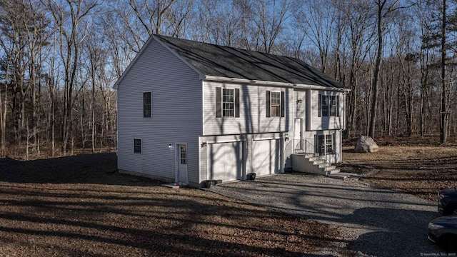 view of outdoor structure featuring driveway, an attached garage, and a forest view