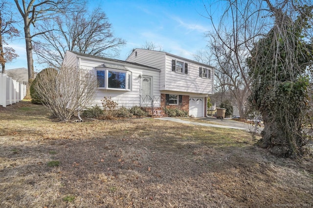 split level home featuring brick siding, an attached garage, concrete driveway, and fence