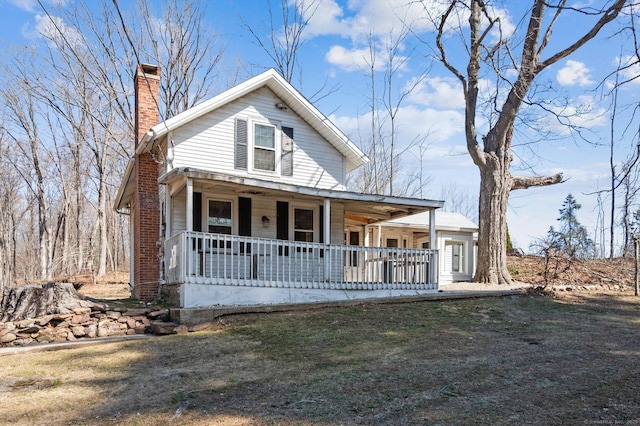 view of front of house with a porch, a front yard, and a chimney