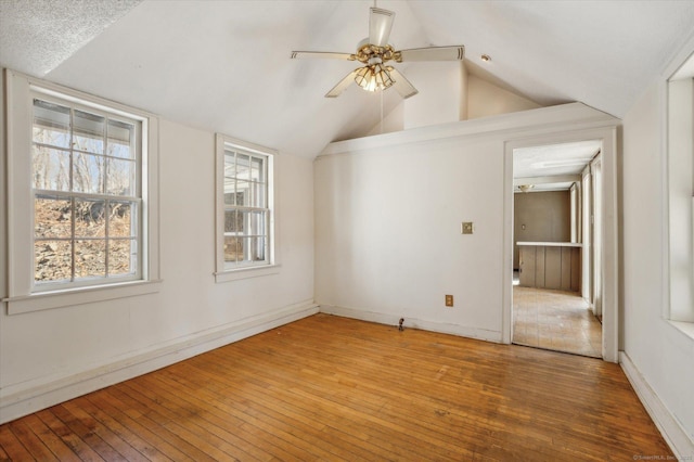 unfurnished room with vaulted ceiling, baseboards, ceiling fan, and wood-type flooring