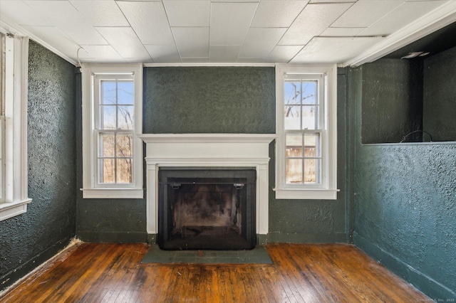 unfurnished living room with a fireplace with flush hearth, hardwood / wood-style floors, and a textured wall