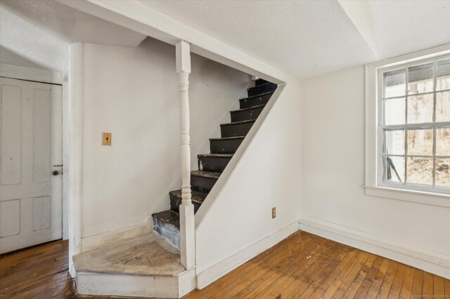 stairway with hardwood / wood-style flooring and a textured ceiling