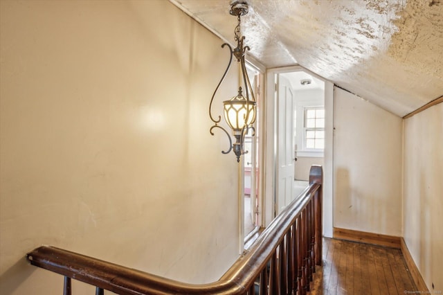 interior space with dark wood finished floors, lofted ceiling, baseboards, and a textured ceiling