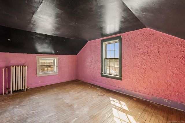 bonus room with baseboards, radiator, vaulted ceiling, and hardwood / wood-style flooring