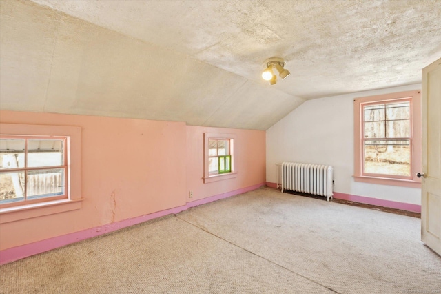 additional living space featuring baseboards, radiator heating unit, carpet floors, vaulted ceiling, and a textured ceiling