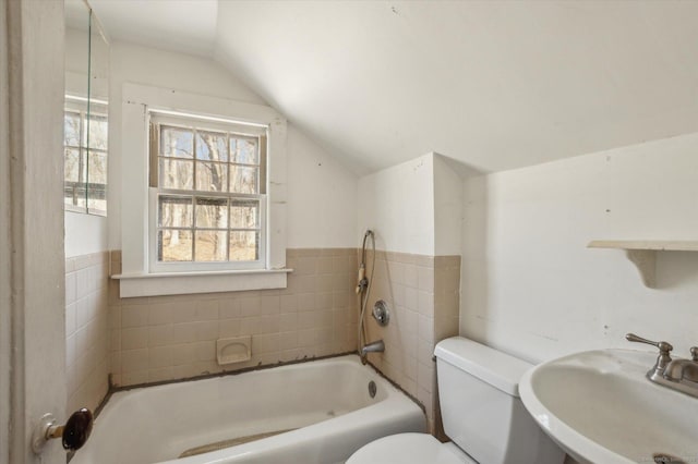 bathroom with vaulted ceiling, a bathing tub, toilet, and a sink