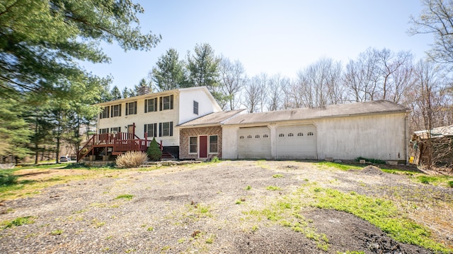 view of front of property featuring a wooden deck, driveway, a chimney, and a garage