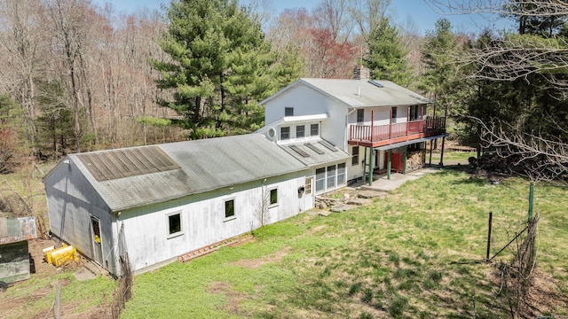 rear view of house featuring a deck, a lawn, and a chimney