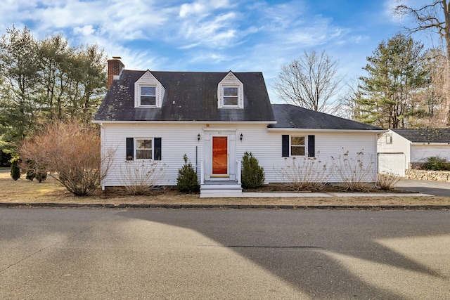 cape cod home with an outbuilding, a chimney, and entry steps