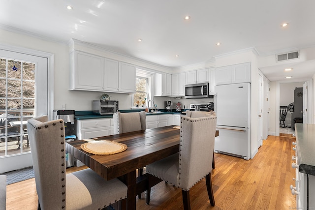 dining area featuring light wood-style flooring, recessed lighting, visible vents, and ornamental molding