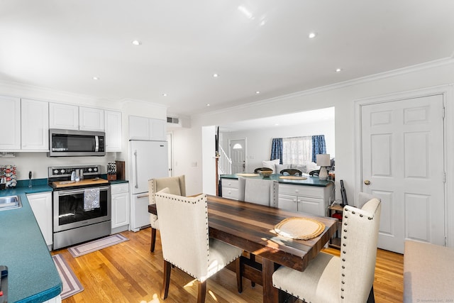 kitchen featuring stainless steel appliances, light wood-style flooring, crown molding, and white cabinetry