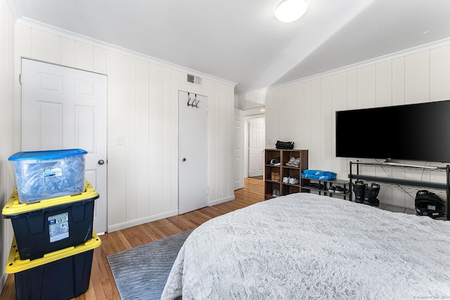 bedroom featuring crown molding, wood finished floors, visible vents, and baseboards