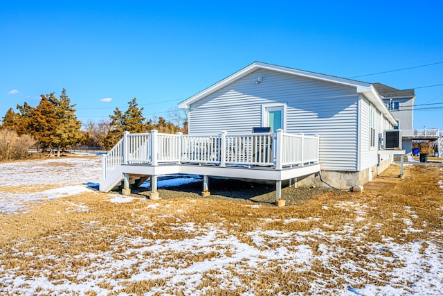 snow covered rear of property with cooling unit and a deck