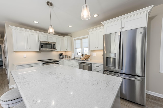 kitchen featuring pendant lighting, wood finished floors, white cabinetry, recessed lighting, and appliances with stainless steel finishes