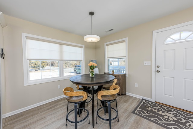 dining space with light wood finished floors, visible vents, and baseboards