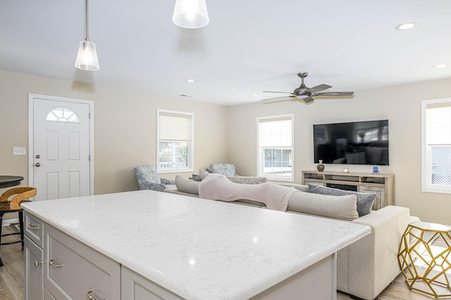 kitchen with light stone counters, recessed lighting, light wood-style floors, and a kitchen island