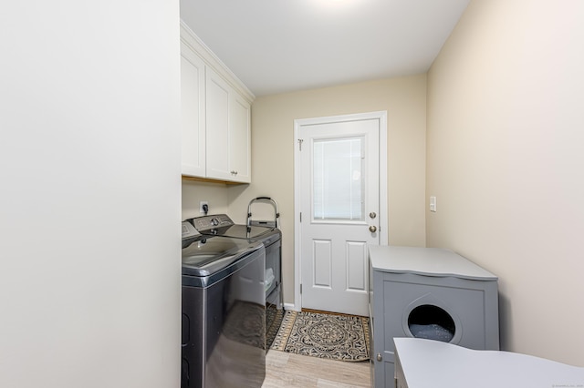 clothes washing area with cabinet space, washer and dryer, and light wood-style floors