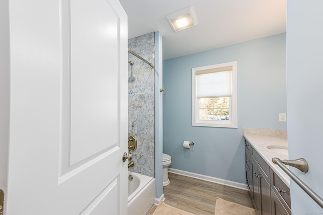 full bath with vanity, wood finished floors, baseboards, bathing tub / shower combination, and toilet