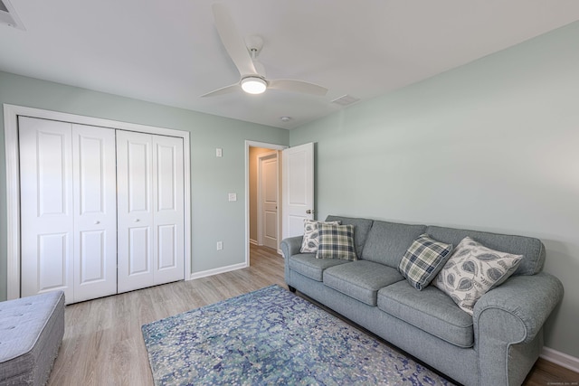 living area with a ceiling fan, wood finished floors, visible vents, and baseboards