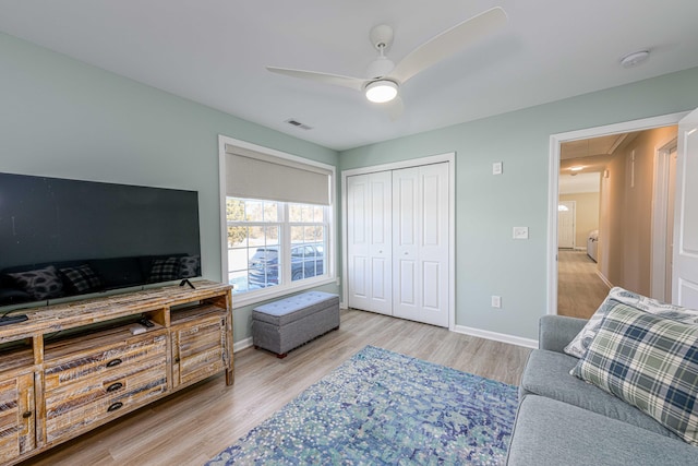 living room with wood finished floors, baseboards, visible vents, attic access, and ceiling fan