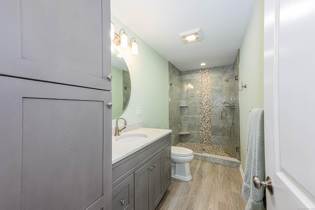 bathroom with a stall shower, toilet, vanity, and wood finished floors