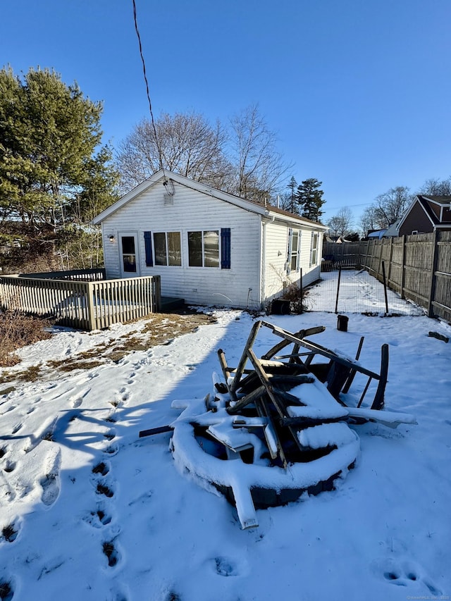 snow covered property featuring brick siding, a deck, and fence