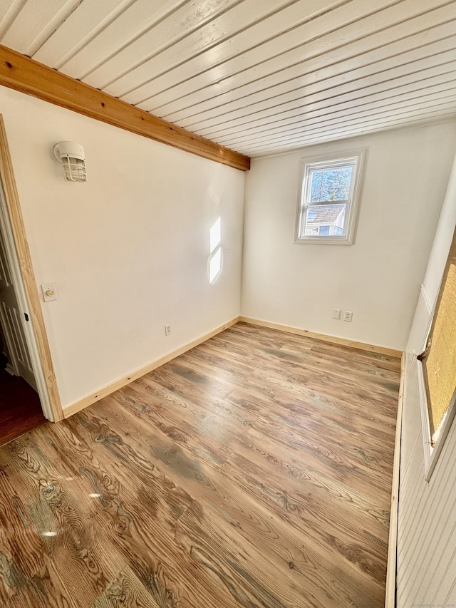 empty room with wood ceiling, wood finished floors, and baseboards