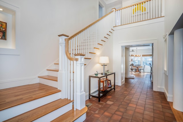 stairs featuring baseboards, a high ceiling, and tile patterned flooring