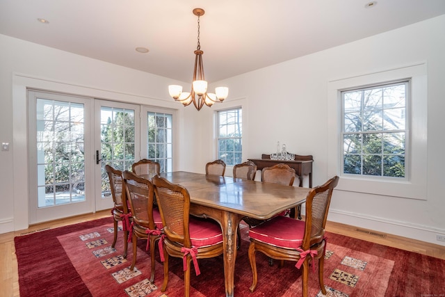 dining area with baseboards, wood finished floors, visible vents, and a chandelier