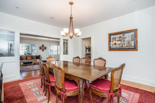 dining room with baseboards, a notable chandelier, and wood finished floors