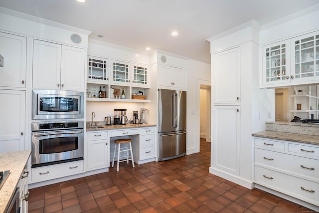 kitchen featuring glass insert cabinets, recessed lighting, appliances with stainless steel finishes, white cabinets, and a sink