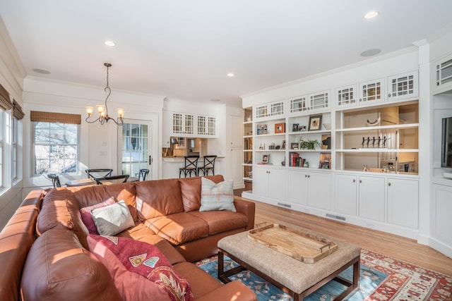 living area with an inviting chandelier, light wood-style flooring, recessed lighting, and ornamental molding