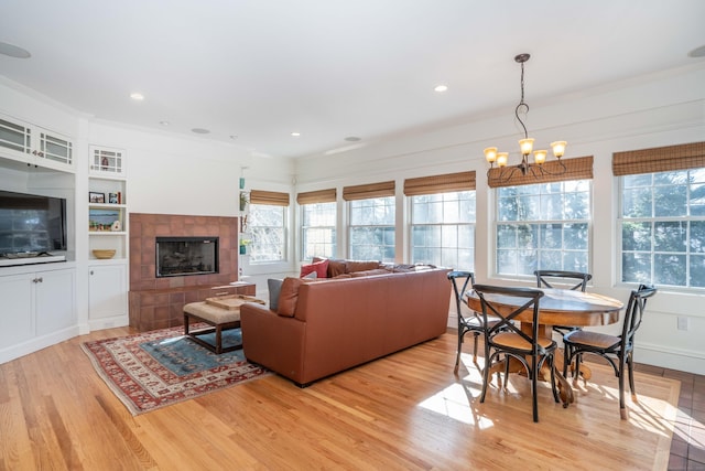 living room with recessed lighting, light wood-type flooring, an inviting chandelier, and a fireplace