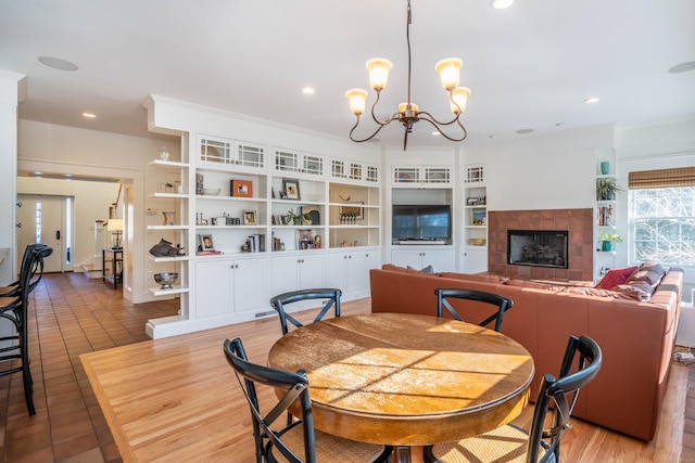 dining area with recessed lighting, built in shelves, an inviting chandelier, and a fireplace