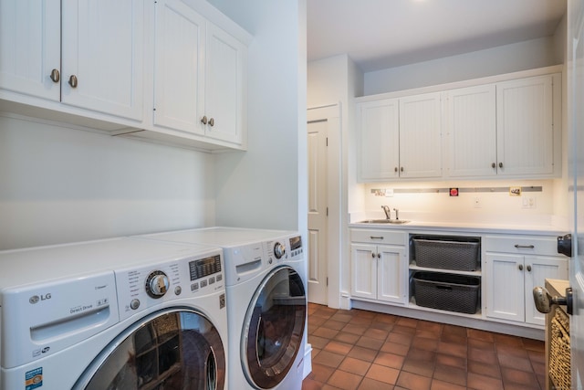 laundry room with cabinet space, dark tile patterned floors, washing machine and dryer, and a sink